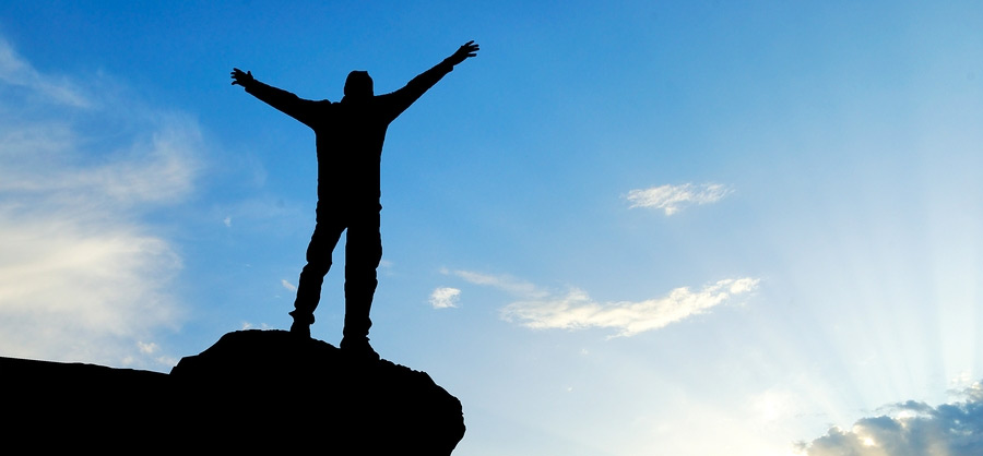 A person standing on top of a rock with arms outstretched.